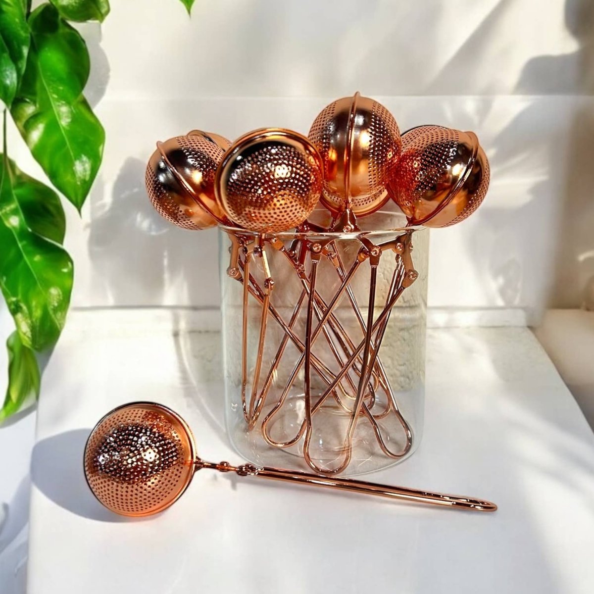 Rose Gold Stainless Steel Tea Strainer | Infuser - marginnotesSet of rose gold tea infusers with a glass jar on a white surface.