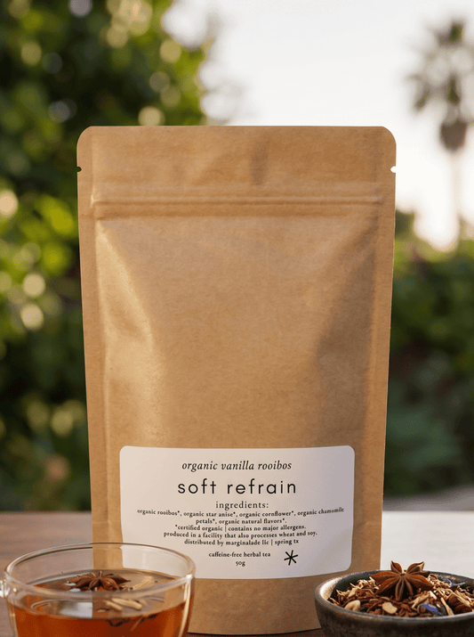 soft refrain loose leaf tea - marginnotesTea packaging with a cup of tea and a bowl of tea leaves on a wooden surface with a blurred green background.