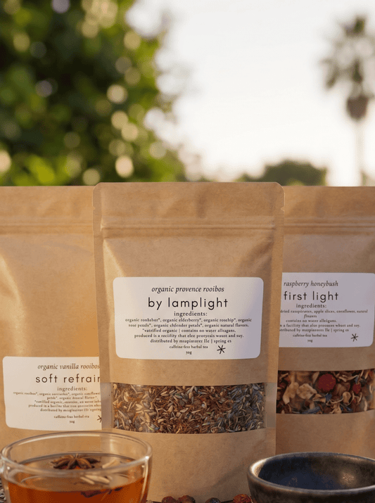 the blends - marginnotesThree tea packages on a wooden surface with a cup of tea and a bowl of dried herbs.
